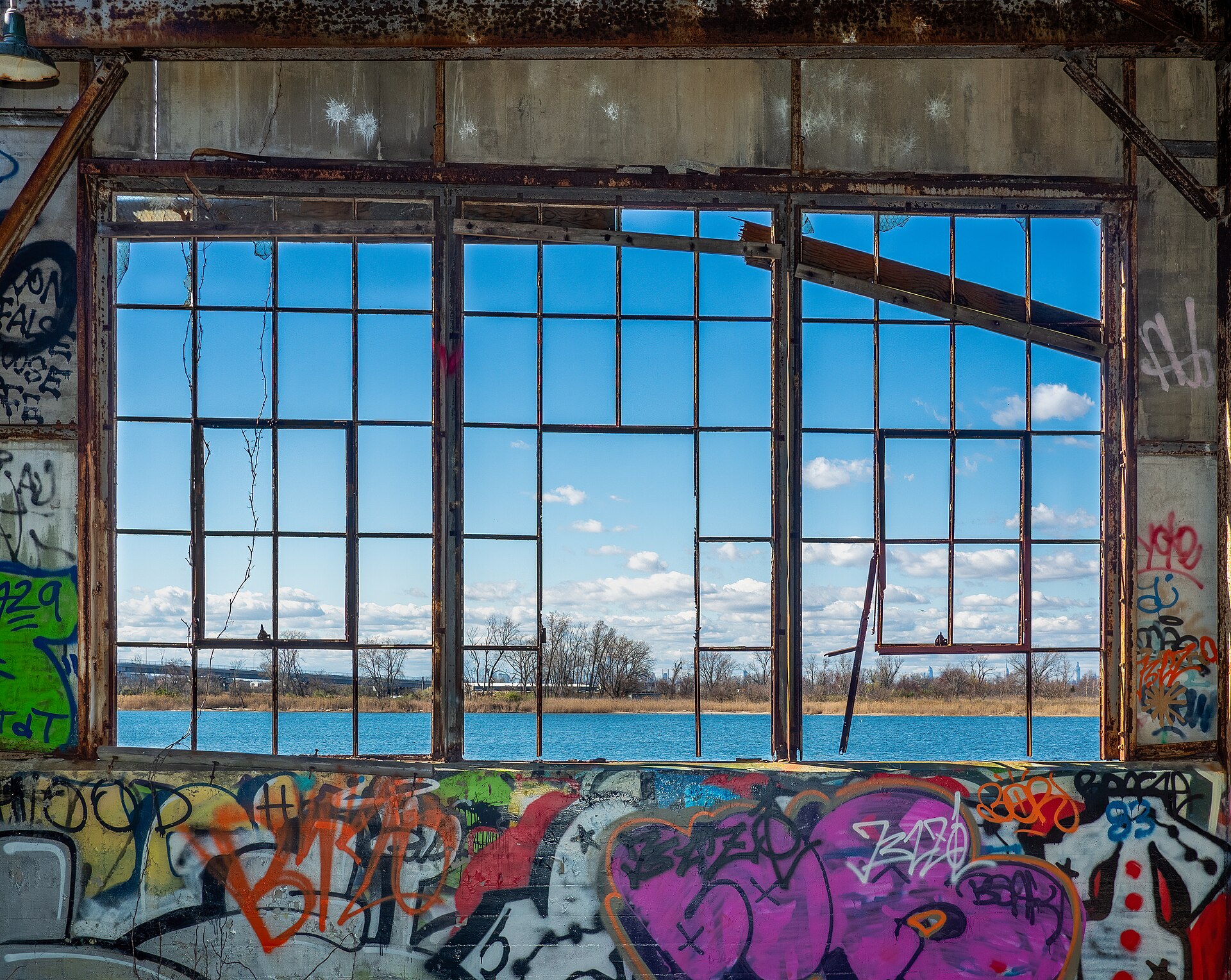 A derelict building with graffiti frames a view of water, illustrating the need for caution and online safety.