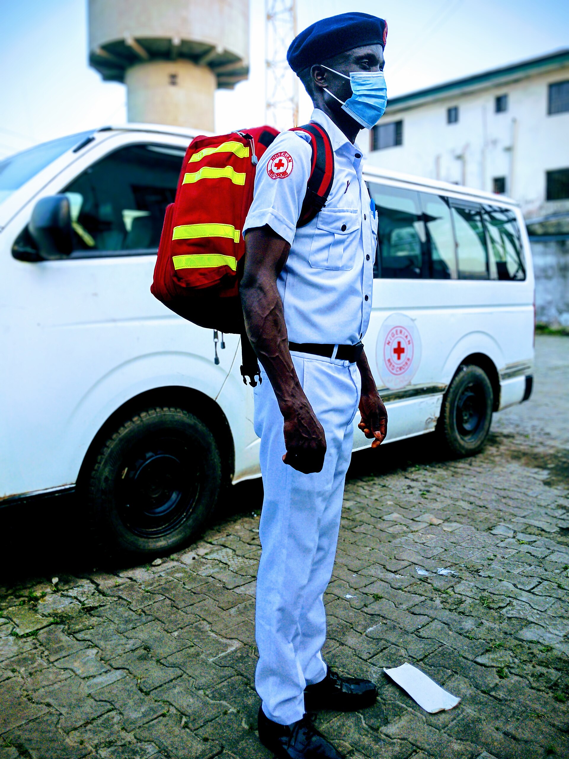 A Red Cross worker near an ambulance demonstrates first aid essentials for home safety.